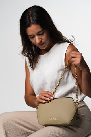 Model sitting with Fanny Pack in color beige with the extra accessory golden chain