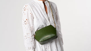 Model wearing a white dress and the Fanny Pack Green with the golden chain accessory