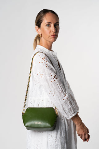 Model is wearing a white dress and the Coneli Fanny Pack Green with extra accessory the goldne chain