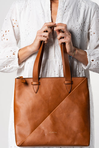 Modle holding with two hands the Coneli Tote Bag in color camel