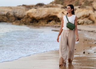 Model walking on beach with Coneli Fanny Pack green as cross-over bag