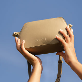 Model holding Coneli Fanny Pack beige into the sky